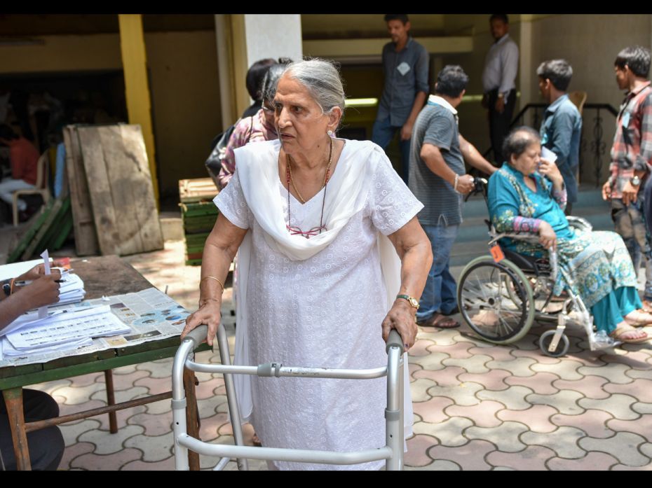 An old lady returns home with the help of a walker after casting her vote, while another elderly lad