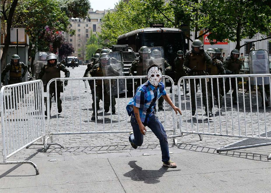 ChileA Mapuche Indian in a mask runs away from riot policemen during a protest against Columbus Day 