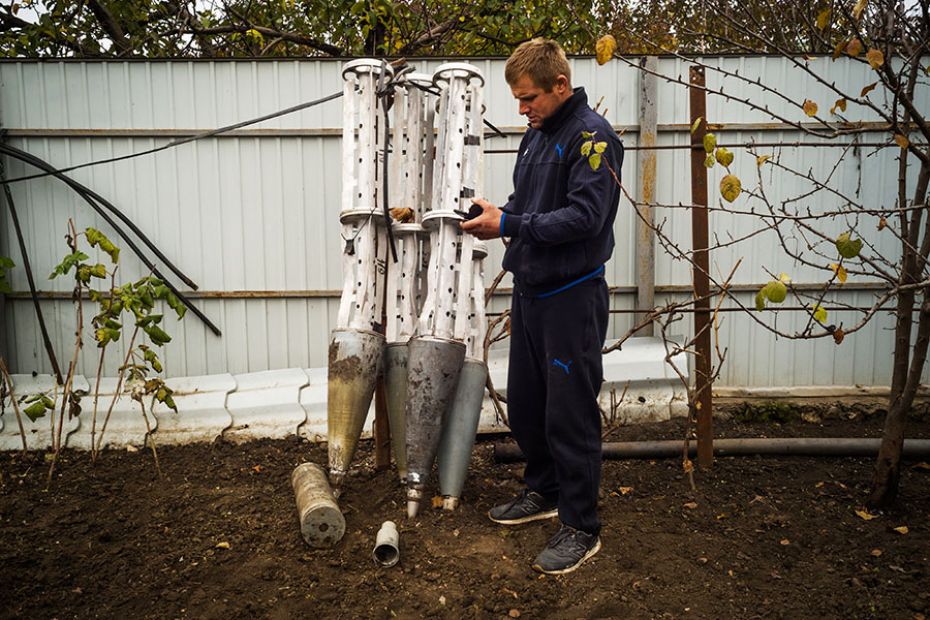 Oleksandr Pashchenko, a farmer, stands next to cluster bomb carriers he collected from his fields in