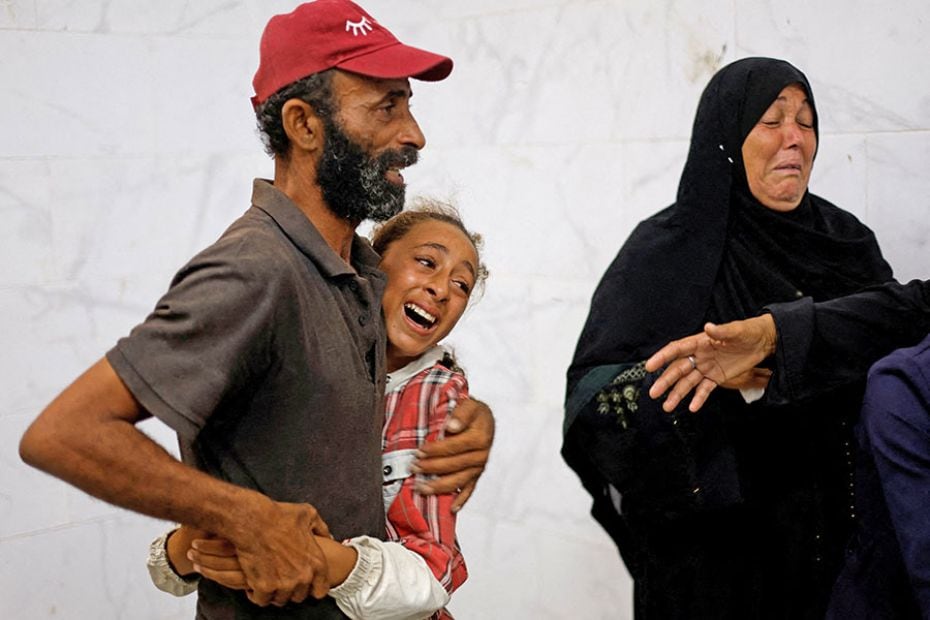 A father and daughter mourn the deaths of their loved ones during the funeral of Palestinians killed