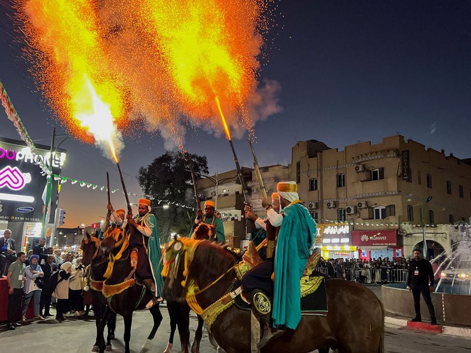 People in traditional attire fire shots in the air during the International Festival of Saharan Tour