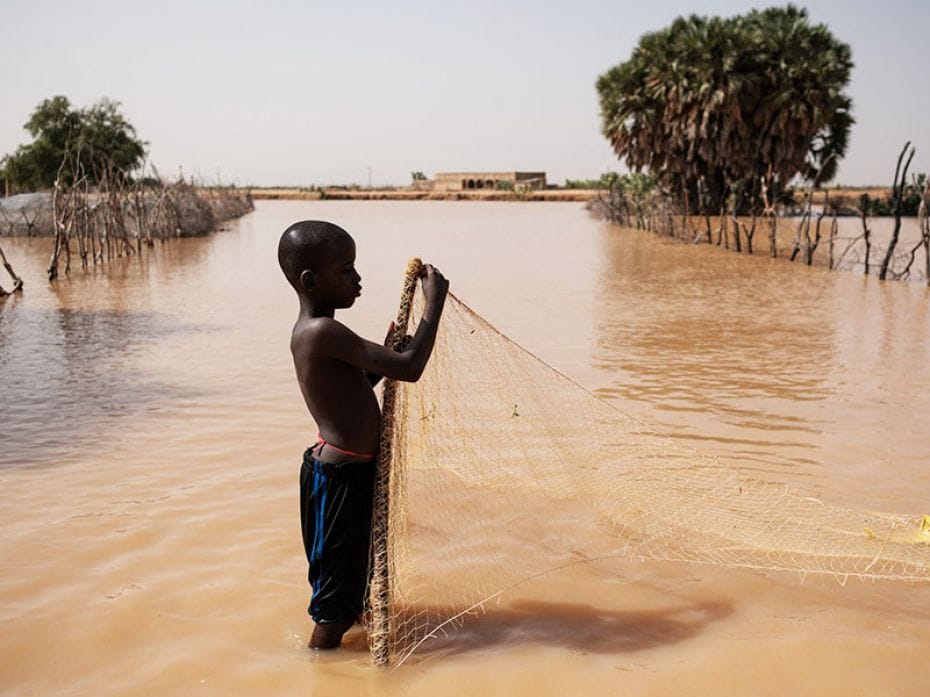 On October 21, 2024, a boy in Odobere, Senegal, puts up a net to catch fish in the flood waters cove