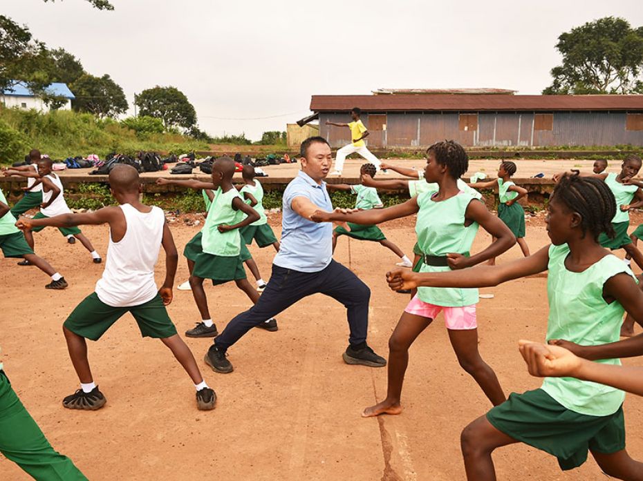 Chinese martial arts teacher Liu Wei (C) practices an exercise with Fourah Bay College Secondary Sch