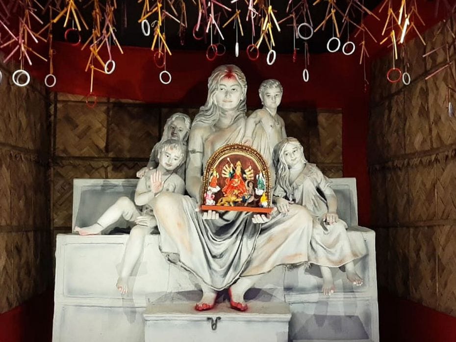 A village woman and her children form the tableau holding the deity Durga in her hands at a woven ba