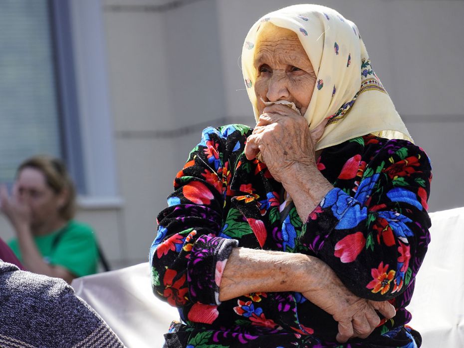 An elder woman waits to receive humanitarian aid after being evacuated from the border settlements t