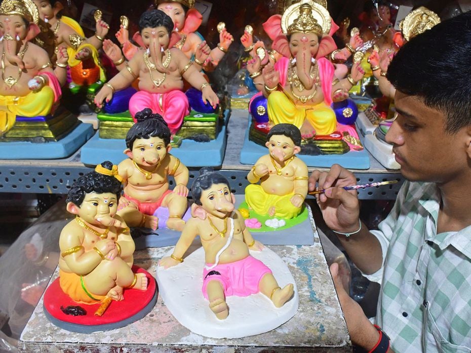 An artist gives final touches to four forms of baby Ganeshas marked by their hairstyles for the Gane